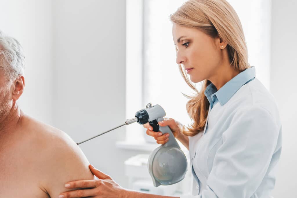 Female doctor dermatologist doing procedure - cryotherapy to patient in clinic