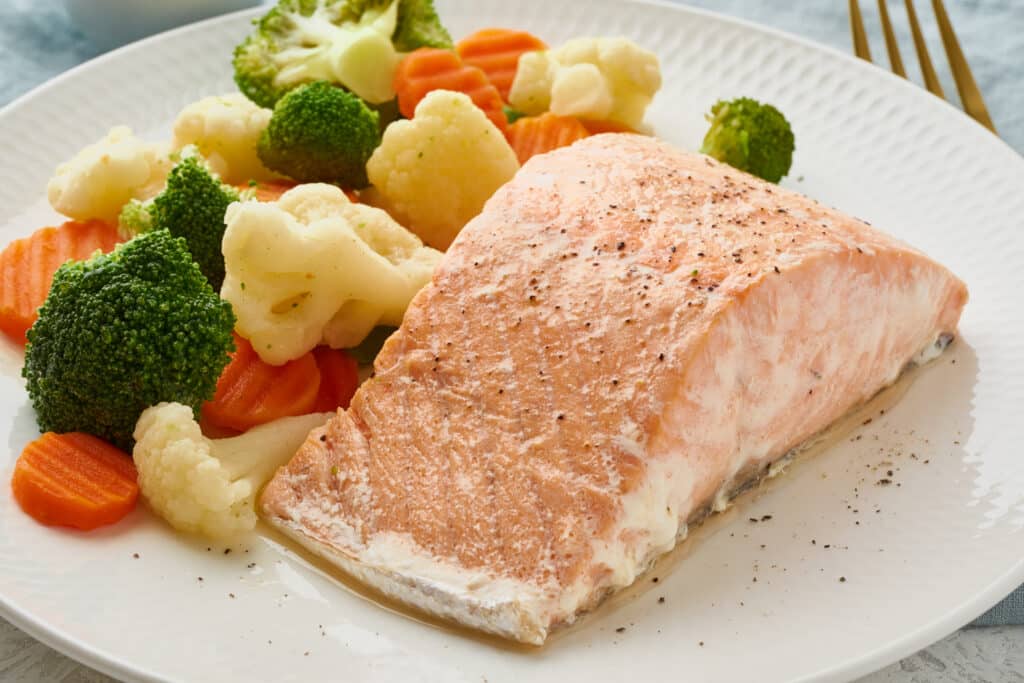 Steam salmon and vegetables, Paleo, keto, fodmap, dash diet. Mediterranean diet with steamed vegetables and fish. Healthy organic concept, gluten free, lectine free, white plate on gray table, macro