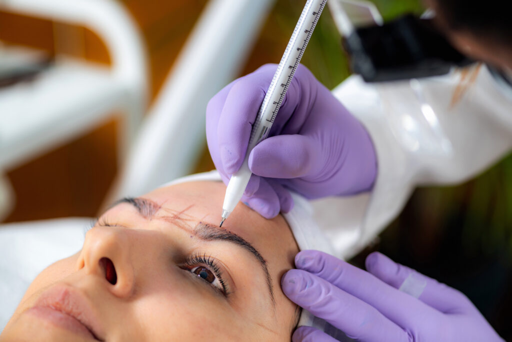 Beautician Addressing the Shape of the Brows Before Microblading.  Semi-Permanent Makeup