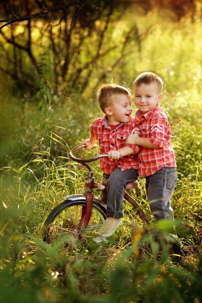 Twin brothers riding a bike in a grassy area
