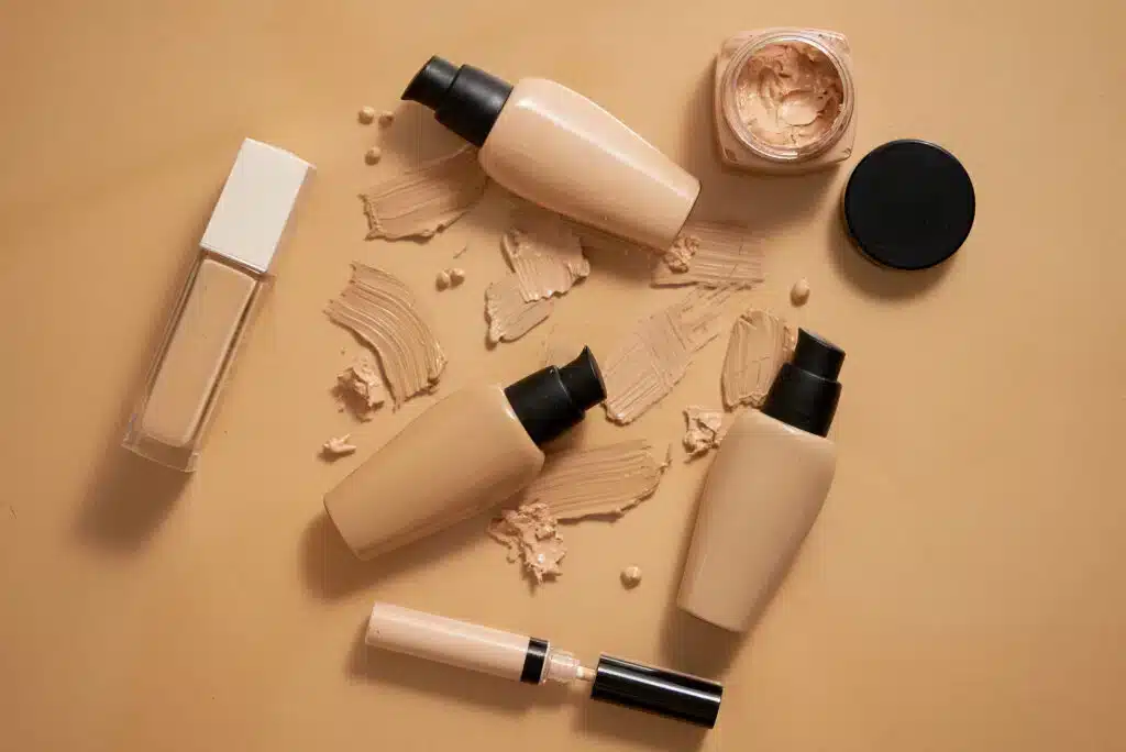 Bottles of makeup foundation and samples on beige background.