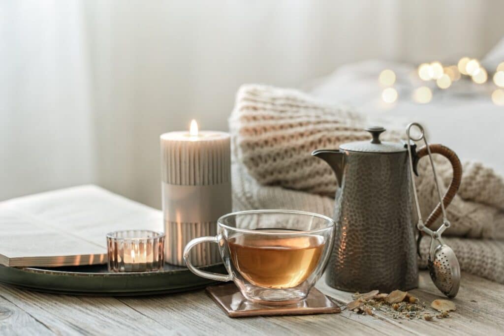 cozy composition with tea, teapot, and candle