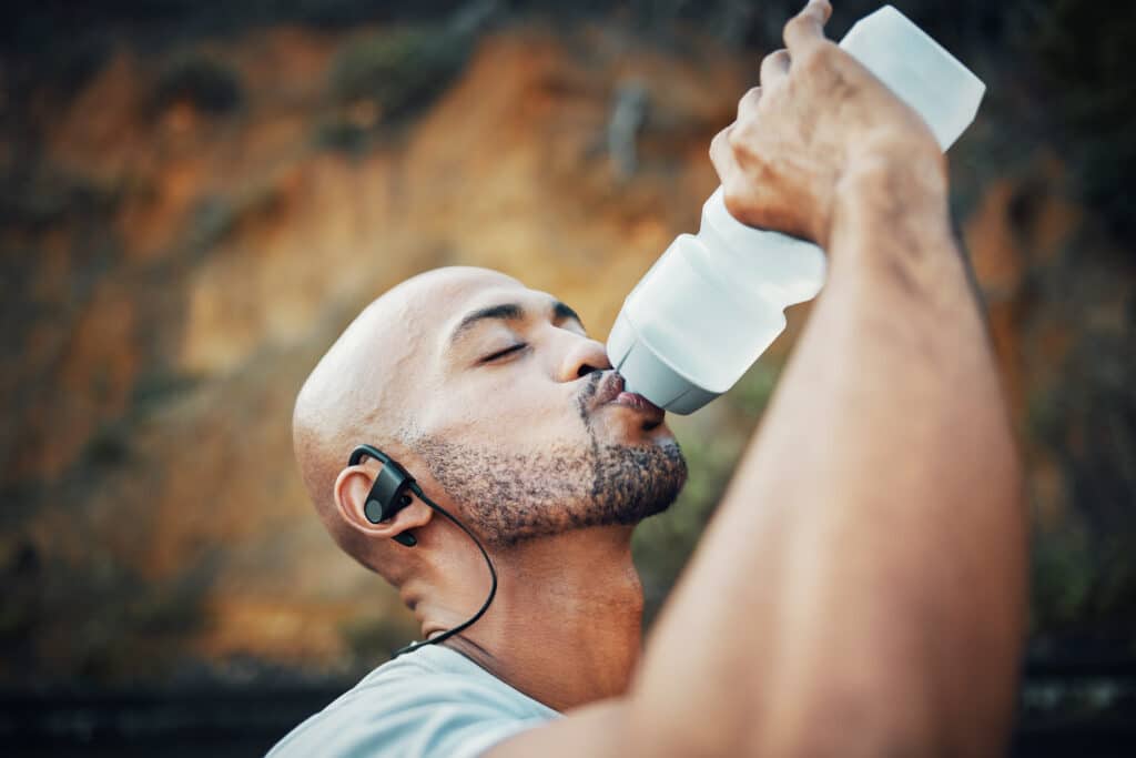 Shot of a sporty young man drinking water while exercising outdoors