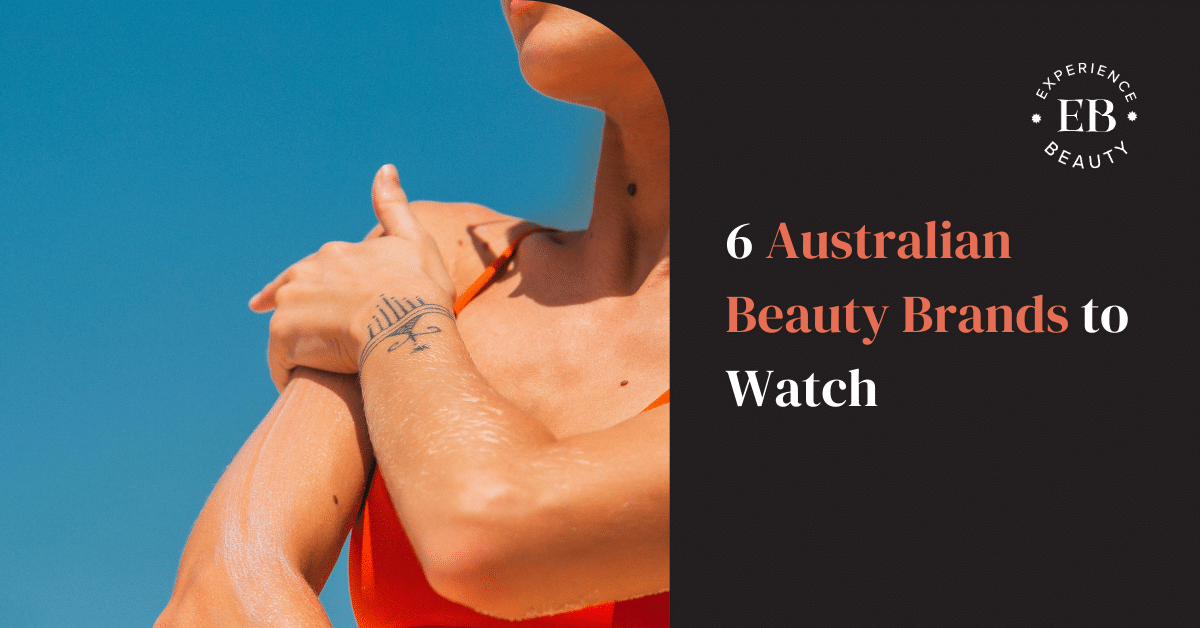 Woman in red bathers applying sunscreen in front of blue sky.